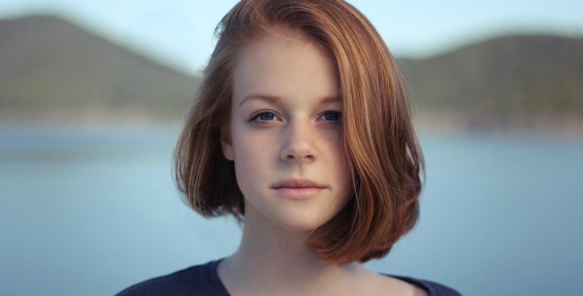 young woman looking at the camera with open water behind her