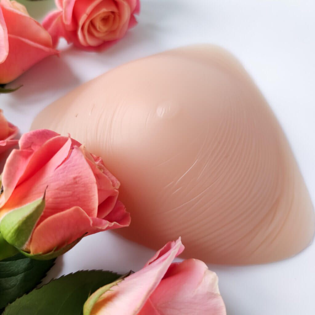 A breast prosthesis near pink roses to be worn as a result of breast cancer surgery.